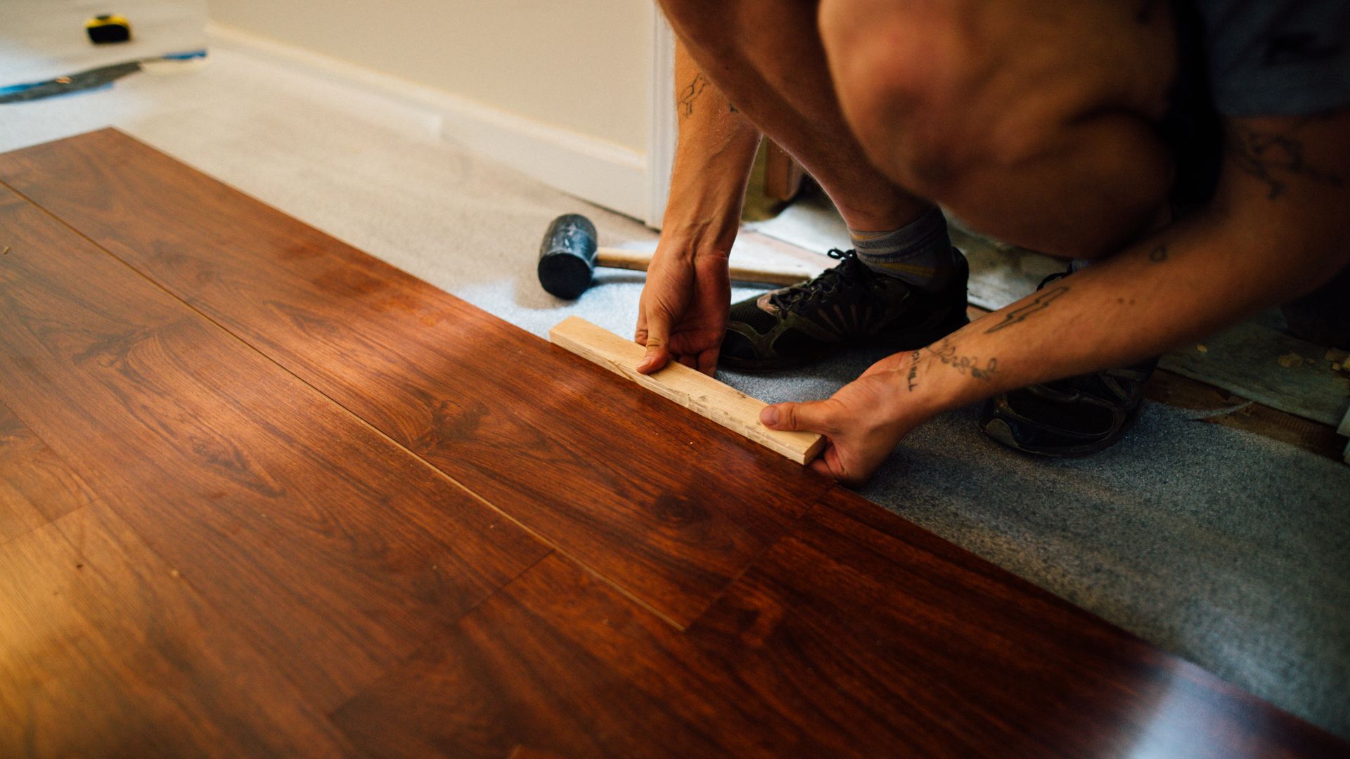 Professional flooring installer laying hardwood floor planks